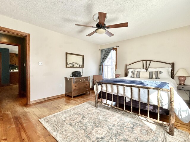 bedroom with a textured ceiling, ceiling fan, and wood-type flooring