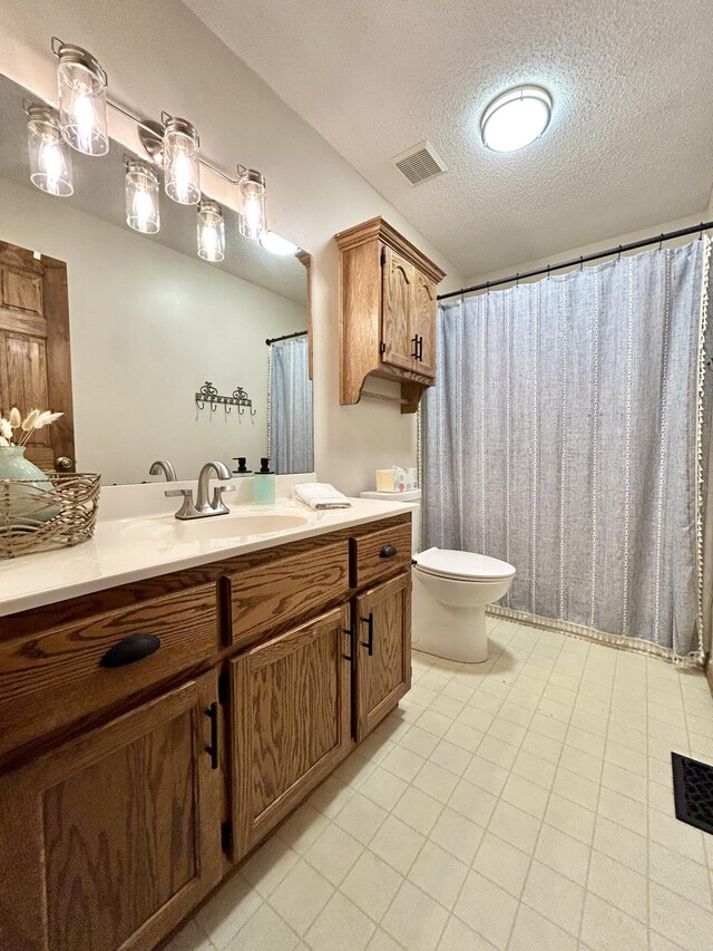 bathroom with a textured ceiling, toilet, and vanity