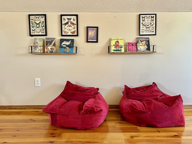 living area featuring a textured ceiling and hardwood / wood-style flooring