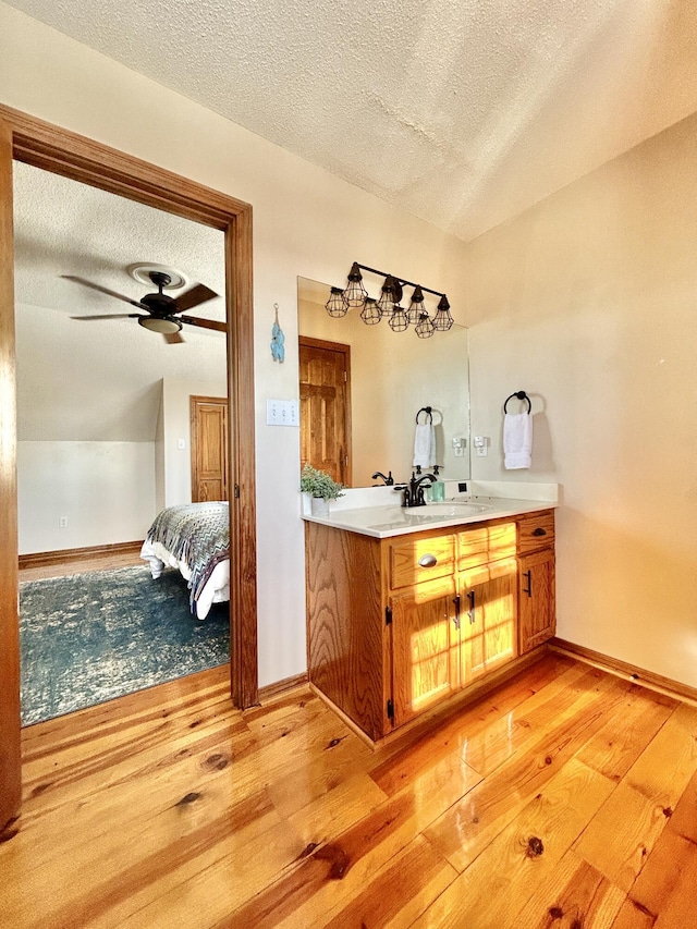 bar featuring a textured ceiling, light hardwood / wood-style floors, sink, vaulted ceiling, and ceiling fan