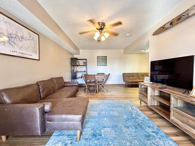 living room featuring ceiling fan, a textured ceiling, and hardwood / wood-style flooring