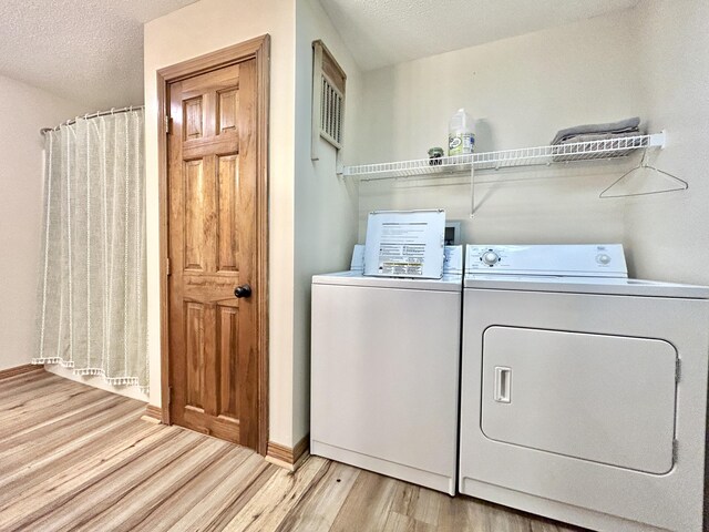 laundry room featuring light wood-type flooring, a textured ceiling, and independent washer and dryer