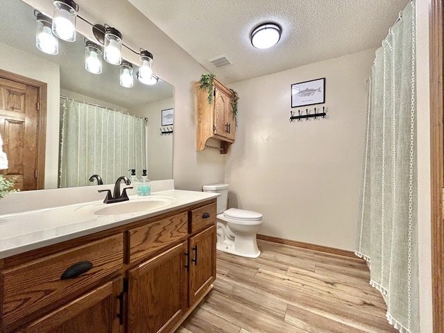 bathroom featuring a textured ceiling, toilet, wood-type flooring, and vanity