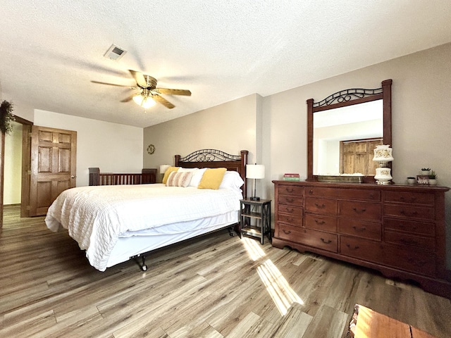 bedroom featuring ceiling fan, a textured ceiling, and light hardwood / wood-style floors