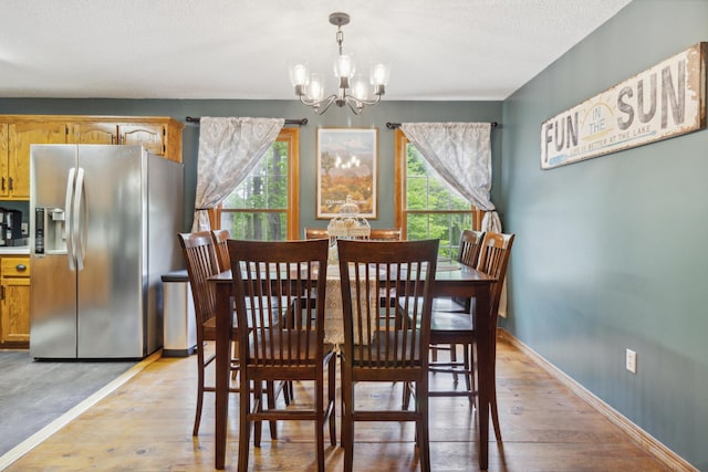 dining area with light hardwood / wood-style floors, a textured ceiling, and a chandelier