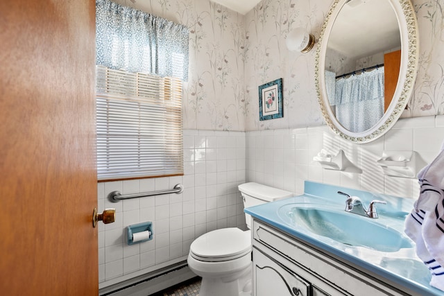 bathroom with tile walls, baseboard heating, toilet, and vanity