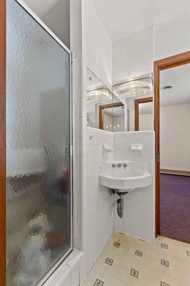 bathroom with tile walls, walk in shower, and sink