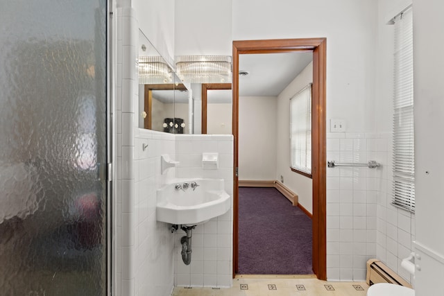 bathroom with tile walls, baseboard heating, an enclosed shower, and sink