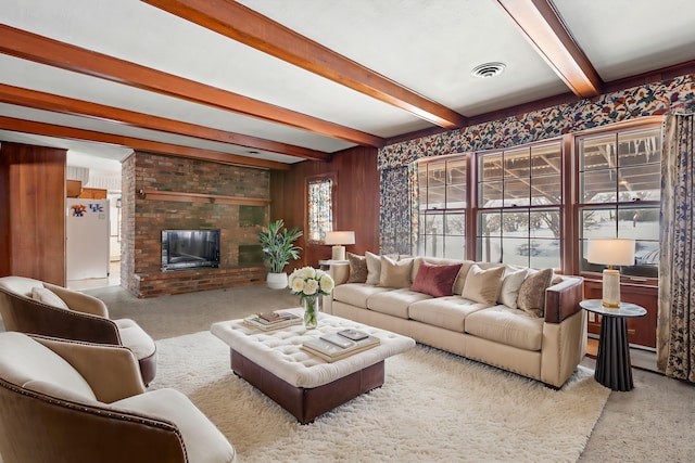 living room featuring a brick fireplace, beam ceiling, a wealth of natural light, and carpet flooring