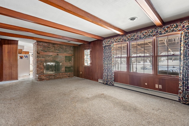 unfurnished living room featuring wooden walls, a baseboard heating unit, a brick fireplace, carpet, and beamed ceiling