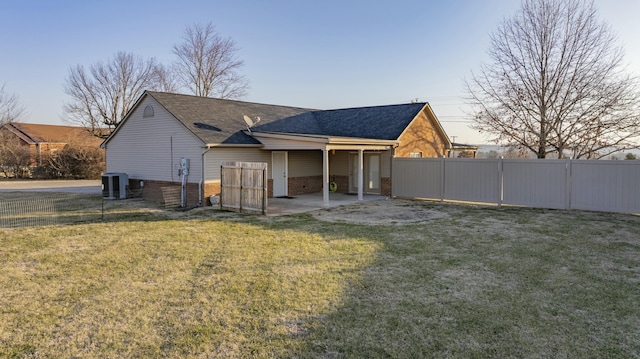 back house at dusk with cooling unit, a yard, and a patio area