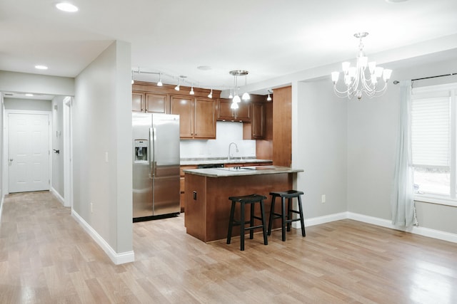 kitchen featuring decorative light fixtures, stainless steel fridge, kitchen peninsula, and a breakfast bar