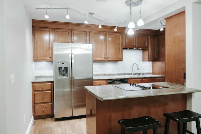 kitchen with sink, a breakfast bar area, hanging light fixtures, kitchen peninsula, and black appliances