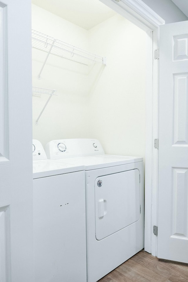 clothes washing area with separate washer and dryer and light wood-type flooring