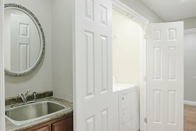 clothes washing area featuring separate washer and dryer, sink, and light wood-type flooring