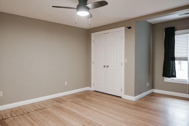 unfurnished bedroom featuring ceiling fan, light hardwood / wood-style floors, and a closet