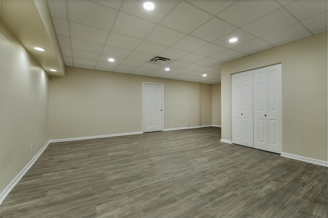 basement featuring a paneled ceiling and dark hardwood / wood-style flooring