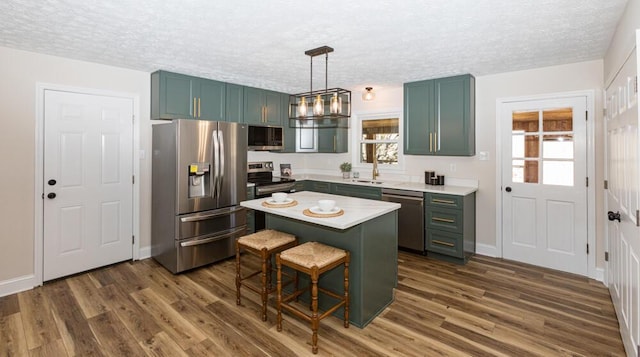 kitchen featuring dark wood-style floors, stainless steel appliances, light countertops, and a healthy amount of sunlight