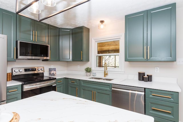 kitchen with stainless steel appliances, green cabinetry, a sink, and light stone counters