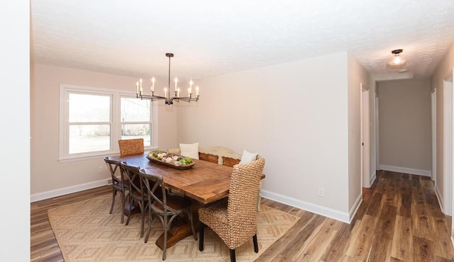 dining space with a chandelier, baseboards, and wood finished floors