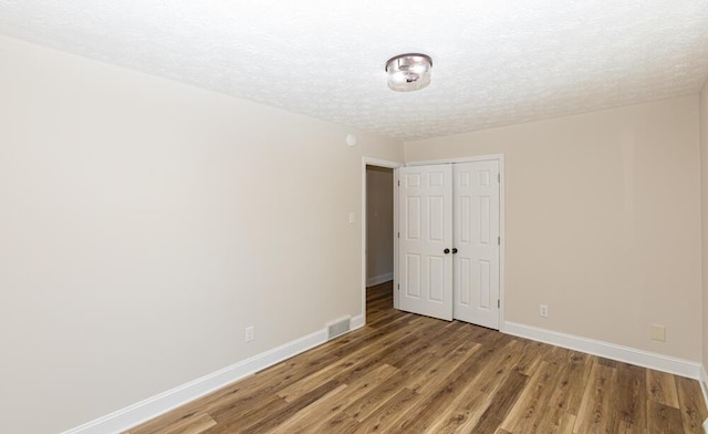 spare room with light wood finished floors, visible vents, baseboards, and a textured ceiling