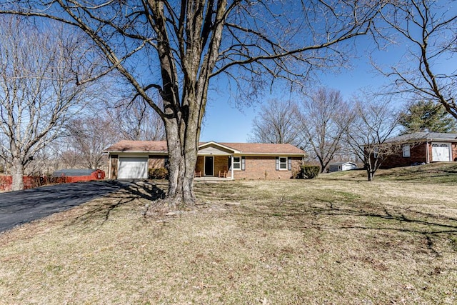 view of front of property featuring a garage, driveway, a front lawn, and brick siding