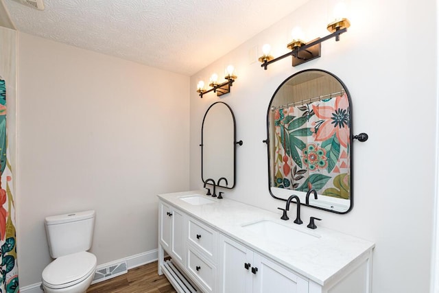 full bath with a textured ceiling, wood finished floors, a sink, and visible vents