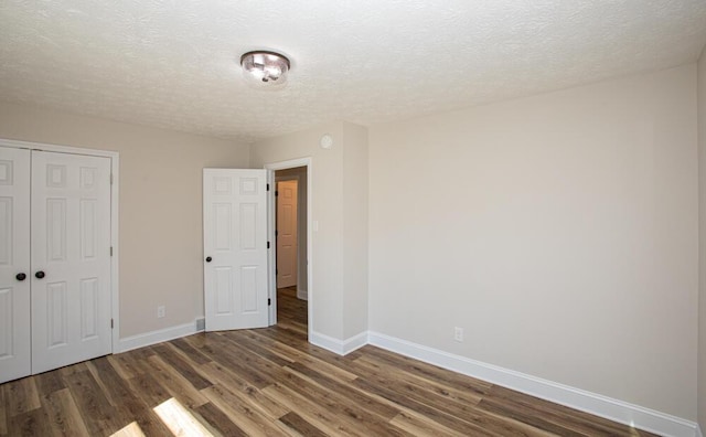 unfurnished bedroom with a textured ceiling, a closet, baseboards, and wood finished floors