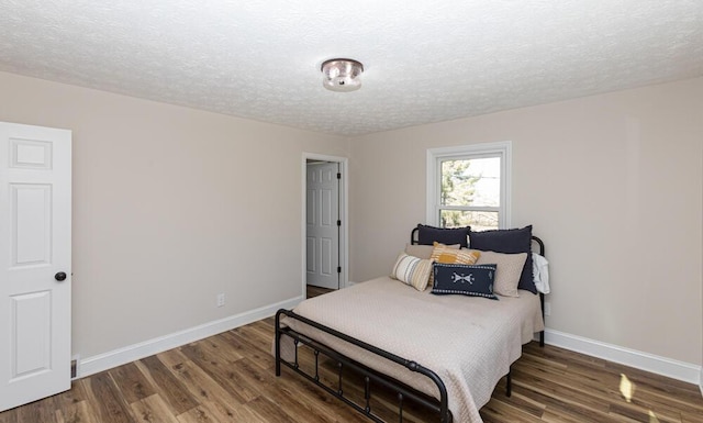 bedroom featuring a textured ceiling, baseboards, and wood finished floors