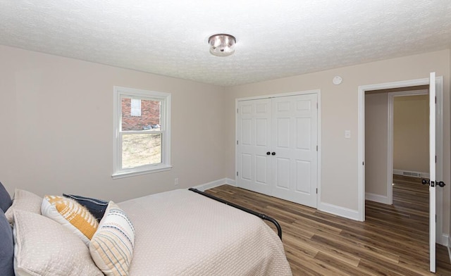 bedroom featuring a textured ceiling, a closet, baseboards, and wood finished floors