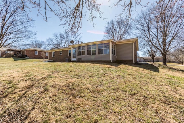 rear view of house featuring a sunroom and a yard