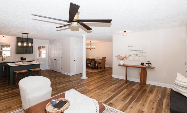 living area featuring a textured ceiling, baseboards, and wood finished floors