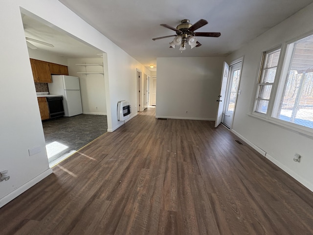 unfurnished living room featuring ceiling fan, dark hardwood / wood-style floors, and heating unit