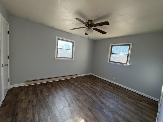 spare room featuring dark hardwood / wood-style flooring, a baseboard radiator, and a healthy amount of sunlight