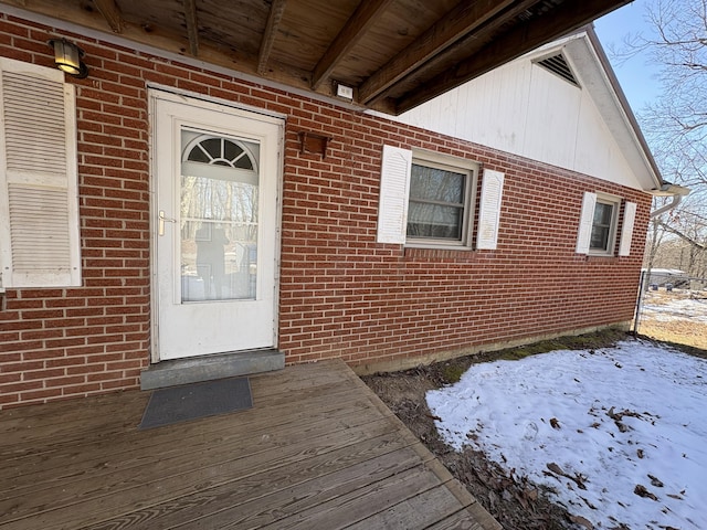 snow covered property entrance featuring a deck