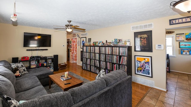 tiled living room featuring ceiling fan and a textured ceiling