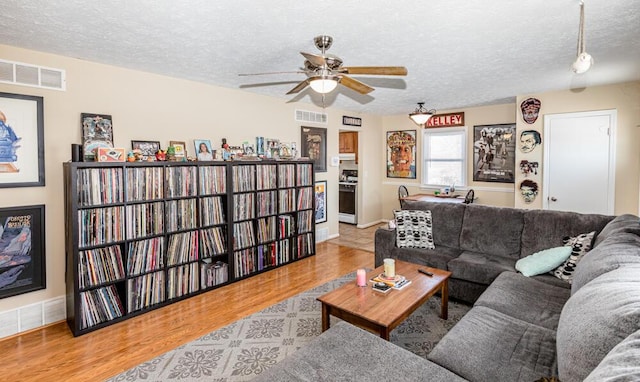 living room featuring ceiling fan, light hardwood / wood-style floors, and a textured ceiling