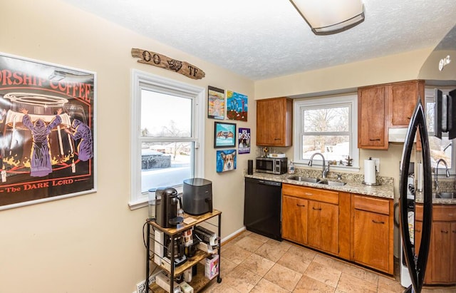 kitchen featuring light stone countertops, a textured ceiling, stainless steel appliances, and sink