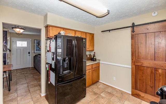 kitchen with a barn door, black fridge, and a textured ceiling