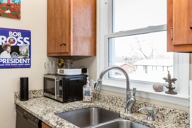 kitchen featuring stainless steel appliances, light stone counters, and sink