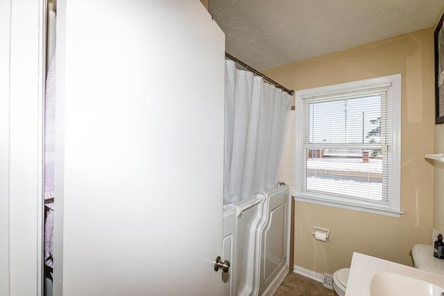 bathroom featuring tile patterned floors, toilet, and a textured ceiling