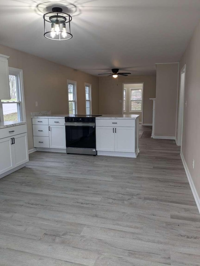 kitchen featuring plenty of natural light, white cabinetry, and range