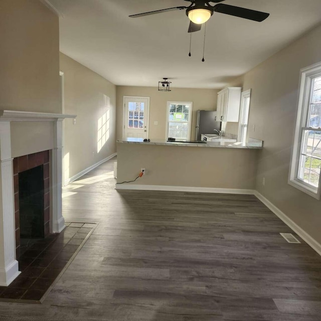 unfurnished living room with dark hardwood / wood-style floors, ceiling fan, and a tile fireplace