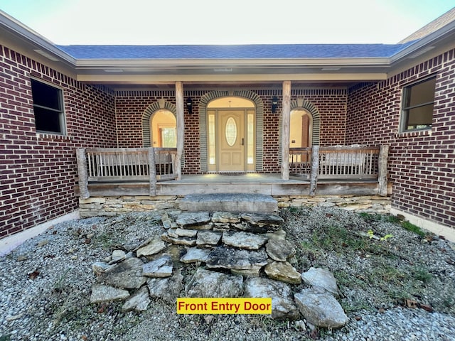 view of exterior entry featuring covered porch