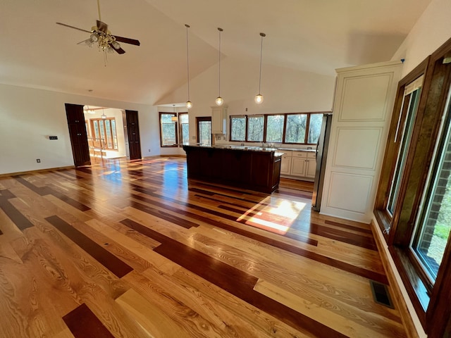 kitchen with light stone countertops, light hardwood / wood-style floors, high vaulted ceiling, and a center island