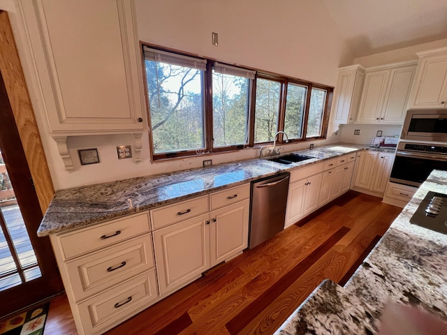 kitchen with lofted ceiling, stone counters, sink, dark wood-type flooring, and stainless steel appliances