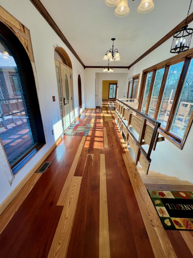 hallway with a notable chandelier, crown molding, and hardwood / wood-style flooring