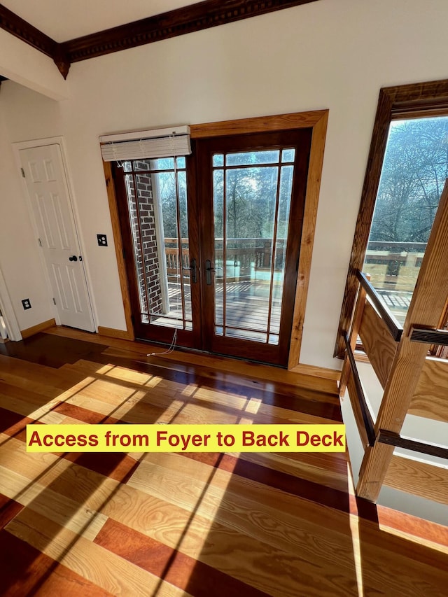 foyer with french doors, plenty of natural light, ornamental molding, and hardwood / wood-style floors