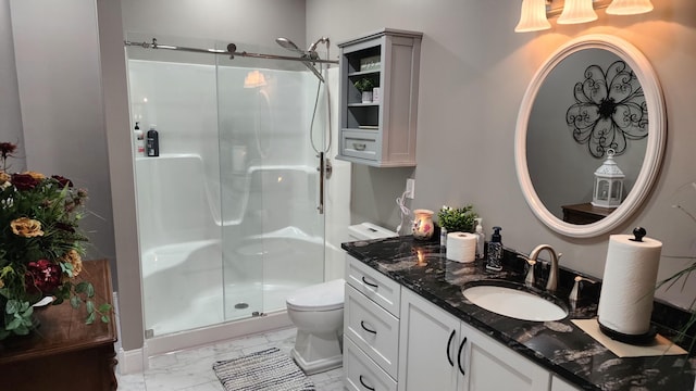 bathroom featuring vanity, a shower with shower door, and toilet