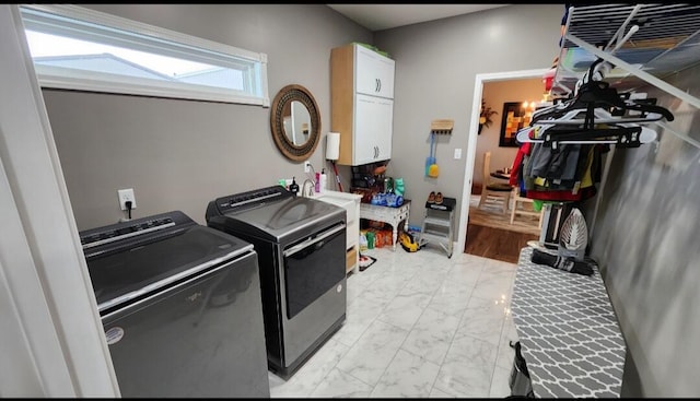 clothes washing area featuring sink, washing machine and dryer, and cabinets